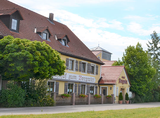 Blick auf das Gasthof Gebäude von der gegenüberliegenden Wiese.