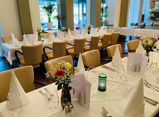 Hochmoderner Restaurantbereich mit bequemen Sitzmöbeln, traumhaften Deckenleuchten und Blick auf die schön beleuchtete Terasse.