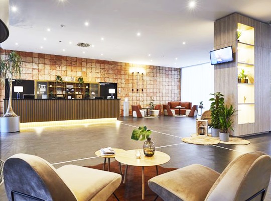 Hellbeleuchtete, große Lobby, mit Pflanzen geschmückt und gigantisch breiten Fliesen.