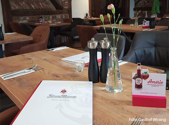 zu sehen ist eine Speisekarte, welche auf einem Tisch liegt, der für ein Essen gedeckt wurde